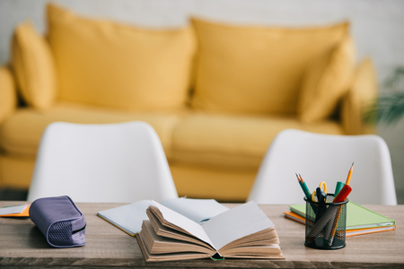 selective focus of wooden desk with open book, copy books, pencil case and stationeryの写真素材
