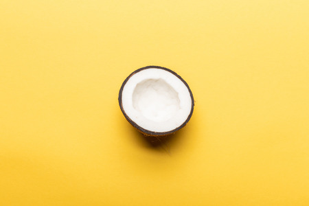 top view of ripe coconut half on yellow background with copy spaceの写真素材