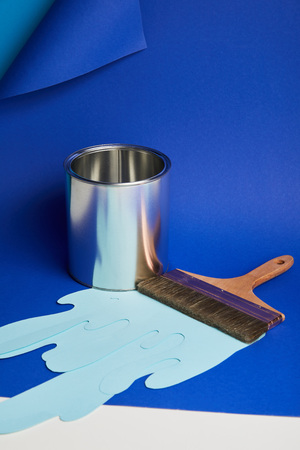 metal shiny can, brush and dripping paper cut paint on bright blue backgroundの写真素材