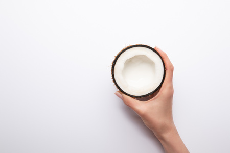 cropped view of woman holding ripe coconut half on white background with copy spaceの写真素材