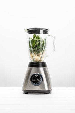 green fresh spinach leaves with cut bananas in blender on whiteの写真素材