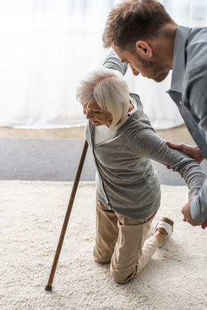 cropped view of man helping sick senior mother with caneの写真素材