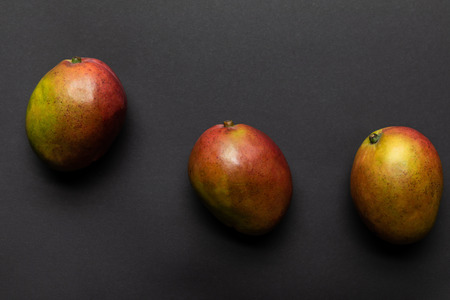 top view of ripe sweet whole mango on black backgroundの写真素材