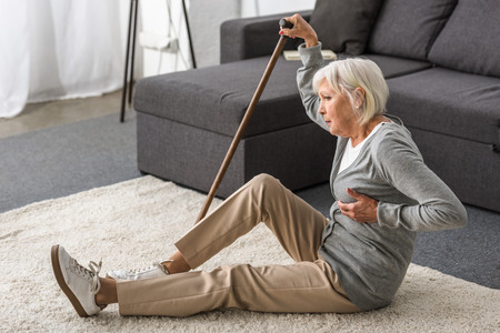 suffering senior woman with heart attack on carpetの写真素材