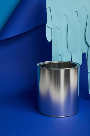 metal shiny can and dripping paper cut paint on bright blue backgroundの写真素材