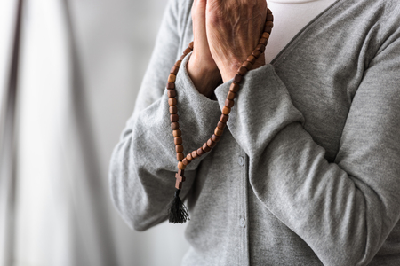 partial view of senior woman praying with wooden rosaryの写真素材