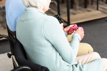 partial view of disabled woman and son playing video game with joysticksの写真素材