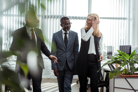 selective focus of happy multicultural partners smiling in officeの写真素材