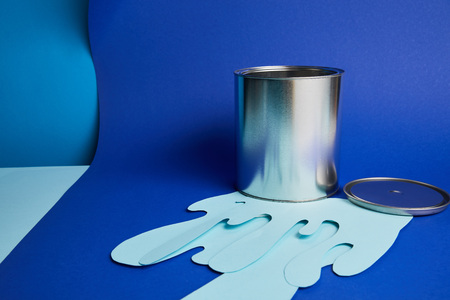 metal shiny can on dripping paper cut paint on bright blue backgroundの写真素材