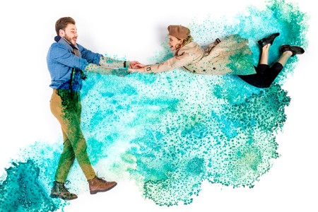Elegant woman levitating in air and holding hands with man on background with watercolor turquoise spillsの写真素材