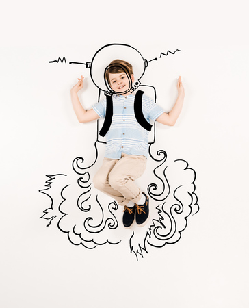 Top view of cheerful kid in astronaut suit gesturing on white backgroundの写真素材
