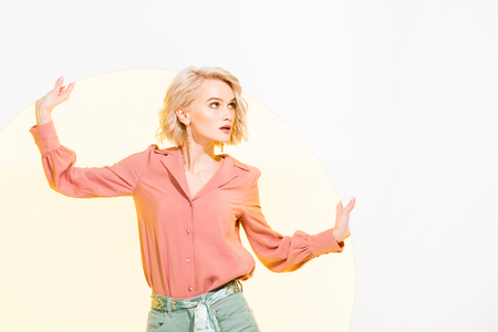 Beautiful fashionable girl in colorful clothes posing on white background with yellow circleの写真素材