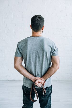 Back view of man holding belt at homeの写真素材