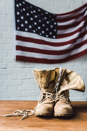 Military boots near American flag with stars and stripes on brick wall backgroundの写真素材
