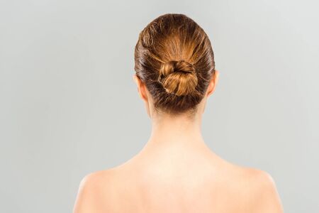 Back view of naked woman standing isolated on grey background