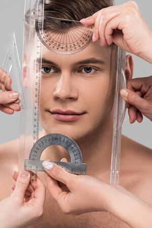 Cropped view of plastic surgeons measuring face with rulers and protractors isolated on grey...