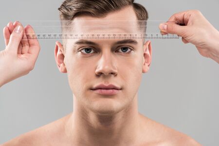 Partial view of plastic surgeons measuring face with ruler isolated on grey backgroundの写真素材