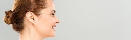 Panoramic shot of cheerful woman smiling isolated on grey backgroundの写真素材