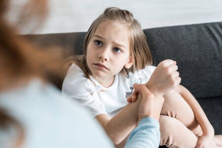 Selective focus of scared kid looking at mother holding hand at homeの写真素材