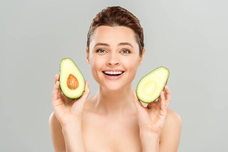 Happy naked woman holding halves of organic avocado isolated on grey backgroundの写真素材
