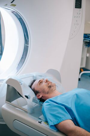 Handsome man lying on ct scanner bed while having tomography testの写真素材