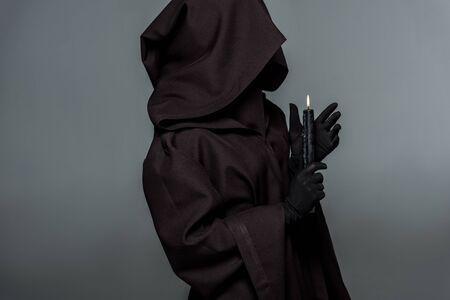 Woman in death costume holding burning candle isolated on grey backgroundの写真素材
