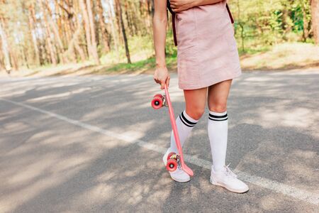 Cropped view of girl in knee socks holding penny board on road