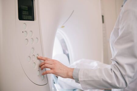 Cropped view of radiologist operating mri machine while patient lying on mri scanner bed