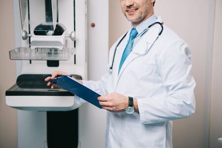 Partial view of doctor holding clipboard while standing at x-ray machineの写真素材