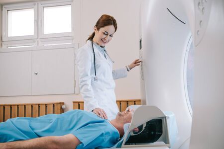 Pretty young radiologist preparing man for tomography diagnostics in mri machineの写真素材