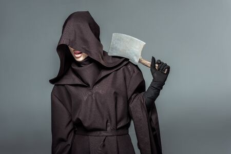 Woman in death costume holding cleaver isolated on grey background
