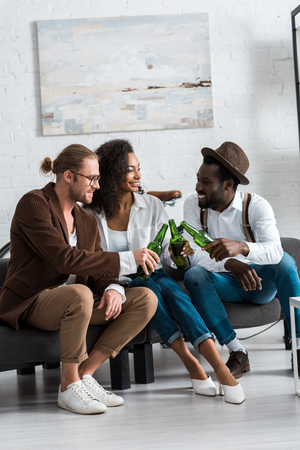 Cheerful multicultural men toasting with happy African American girl in living roomの写真素材