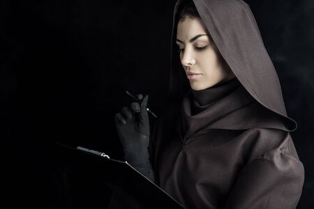 Woman in death costume holding clipboard on black backgroundの写真素材