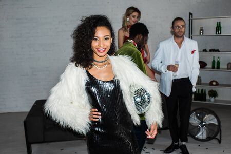 Selective focus of African American girl holding disco ball while standing near friends