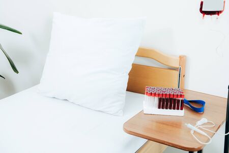 Bed, wooden table, test tubes and blood bag in clinicの写真素材