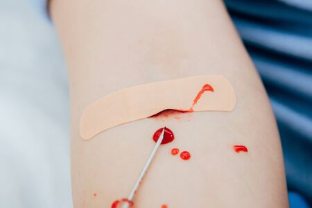 Partial view of woman with adhesive bandage, blood drops and syringeの写真素材
