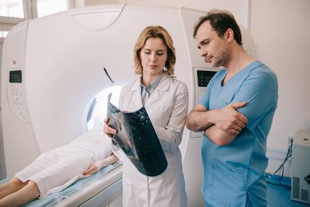 Thoughtful doctors looking at x-ray diagnosis during patients diagnostics on ct scannerの写真素材