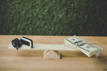 pack of dollar banknotes and car key balancing on swing on green backgroundの写真素材