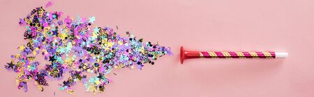 Panoramic shot of party horn with sparkling confetti on pink backgroundの写真素材