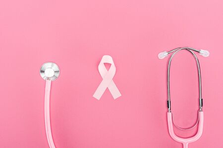 top view of stethoscope and pink breast cancer symbol on pink background
