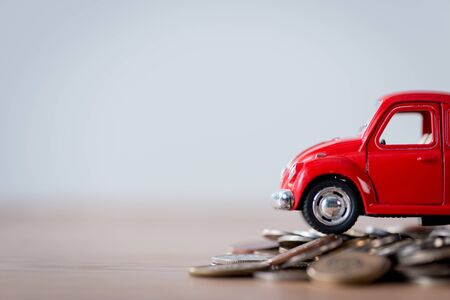 red miniature car and metal coins on wooden surface isolated on greyの写真素材