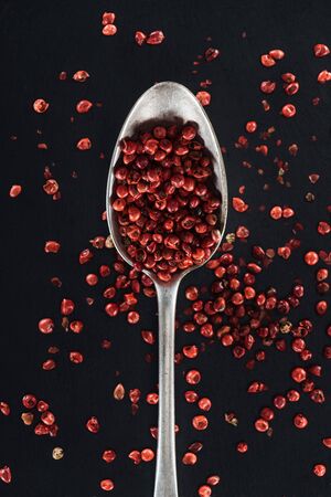top view of red pepper in silver spoon on black background
