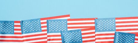 panoramic shot of national patriotic american flags on blue background