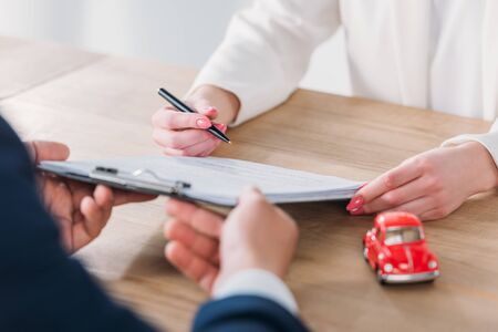 partial view of client signing contract on clipboard in managers hands