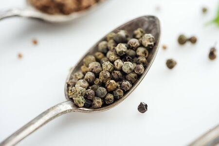 close up view of pepper in silver spoon on white backgroundの写真素材