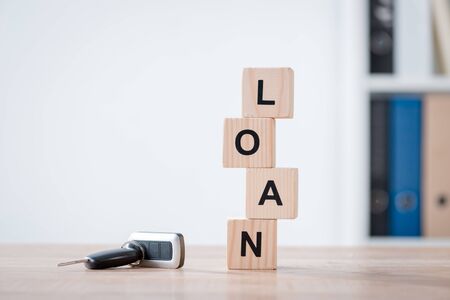 car keys and wooden cubes with word loan on wooden tabletop surface in office