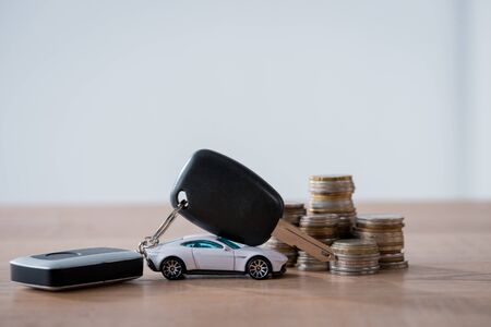 toy car, metal coins and car keys on wooden surface isolated on greyの写真素材