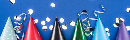 Panoramic shot of party hats and confetti on blue backgroundの写真素材
