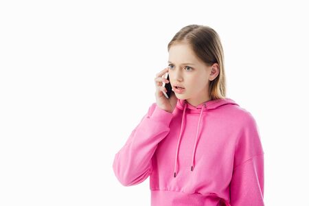 upset teenage girl in pink hoodie talking on smartphone isolated on whiteの写真素材