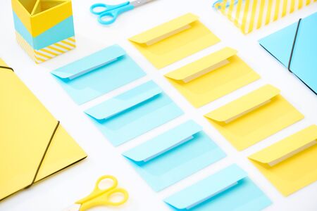 flat lay of colourful envelopes, scissors, folders, pencil case and pencil box on white backgroundの写真素材